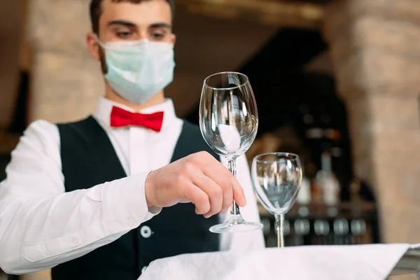 Un cameriere con una maschera protettiva medica serve il tavolo del ristorante. — Foto Stock