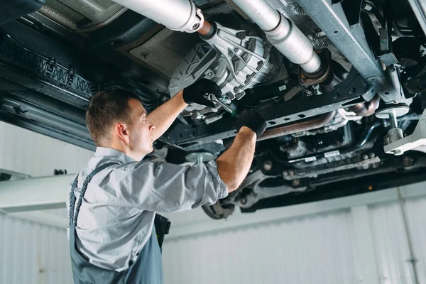 Retrato de un mecánico reparando un coche levantado. — Foto de Stock