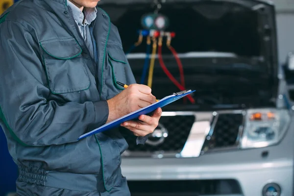 Mechanic maintaining car record on clipboard at the repair shop. — Stock Photo, Image