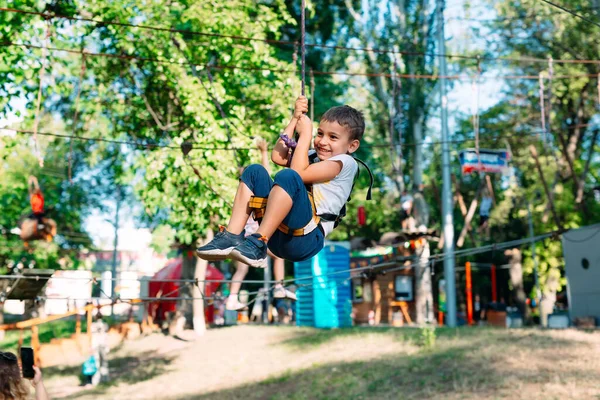 Enfant heureux profitant d'une activité dans un parc d'aventure d'escalade. — Photo