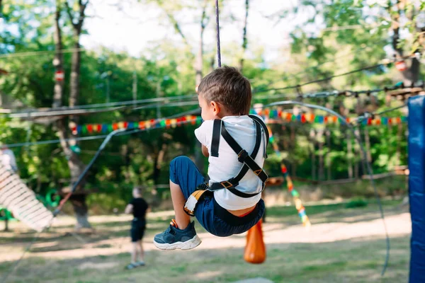 Boldog gyerek élvezi tevékenység egy hegymászó kaland park. — Stock Fotó