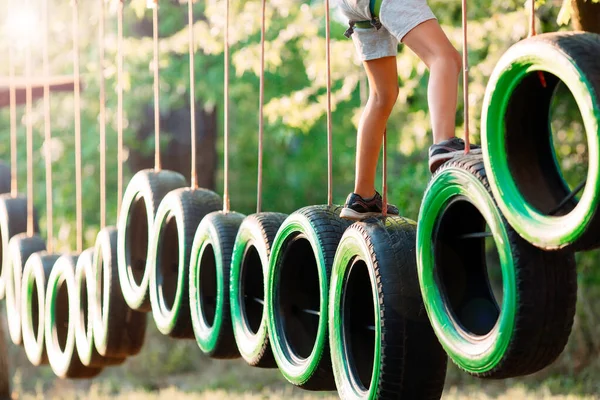Corda Park. Um menino passa um obstáculo em pneus em um parque de corda. — Fotografia de Stock