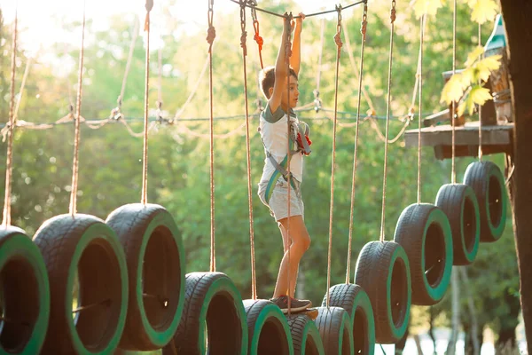 Touwenpark. Een jongen passeert een obstakel op banden in een touw Park. — Stockfoto