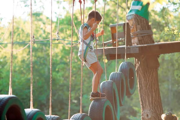 Parque de cuerdas. Un niño pasa un obstáculo en los neumáticos en una cuerda Park. — Foto de Stock