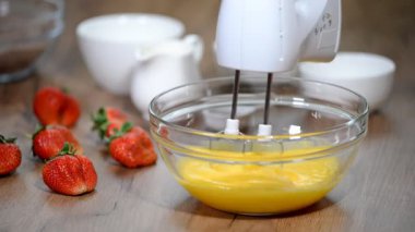 Dövülmüş yumurta bir kapta Mikser çırpma aletleri ile.
