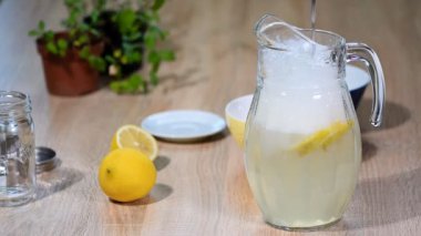 Limon bir sürahi içinde su dökün. Pırıl pırıl cam soda içecek limonata buzlu su ve limon dilim beyaz zemin üzerine kireç