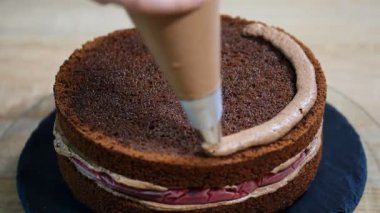 Tanınmayan kadın pasta yemek iştah açıcı katman kek mutfak üzerine sıkma krem çikolata.