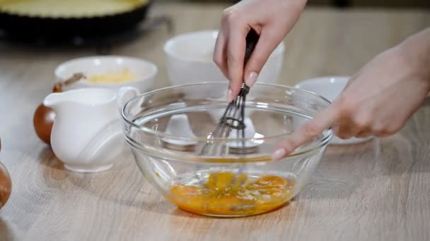 Шеф-повар выбрасывает яйца в стеклянную миску на кухонный стол — стоковое видео