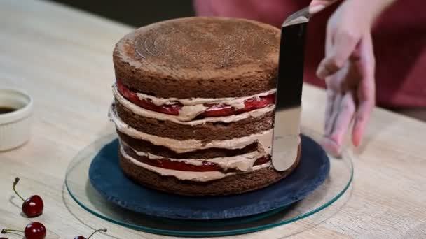 Preparação passo a passo do bolo de grife preto. O confeiteiro cobre o bolo com creme . — Vídeo de Stock