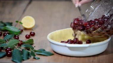 Evde taze ve tatlı ev yapımı kirazlı turta Kırmızı Kiraz çiğ hamur içine koyarak bir mutfak tezgahı üzerinde hazırlanıyor.