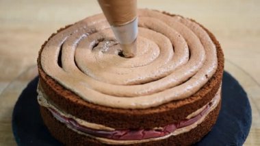 Tanınmayan kadın pasta yemek iştah açıcı katman kek mutfak üzerine sıkma krem çikolata.