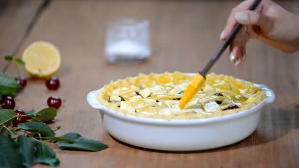 Zutaten für Kuchen mit frischem Kirschkuchen gefüllt backen. Weibchen bereiten Kirschtorte zu. Eierwäsche auf Tortenoberseite verteilen — Stockvideo