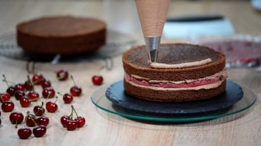 Tanınmayan kadın pasta yemek iştah açıcı katman kek mutfak üzerine sıkma krem çikolata.