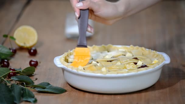Ingredienser för bakning kakor fyllda med färska körsbärspaj. Kvinna som förbereder körsbärspaj. Sprida ägg tvätt över toppen av pajen. — Stockvideo