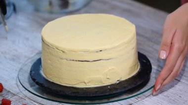 Pasta şefi kendi elleri ile bir pasta yapar ve onu çilek ile süsle.