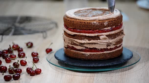 Unrecognizable pasticceria femminile cuoco spremitura crema di cioccolato su torta strato appetitoso in cucina . — Video Stock