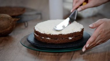 Kadının el yayılan beyaz çikolata sünger kek üzerine krema ne arar.