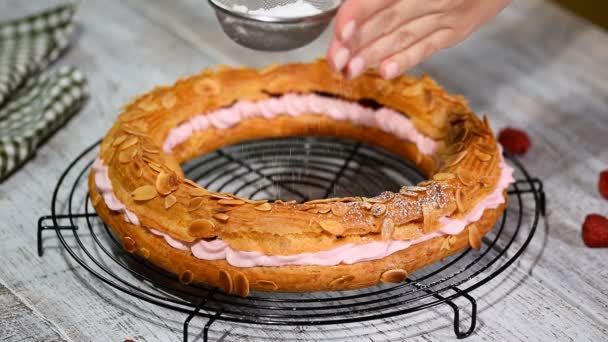 Peneirando açúcar em pó sobre um paris brest . — Vídeo de Stock