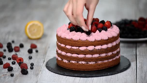 Кондитер украшает торт ягодами . — стоковое видео