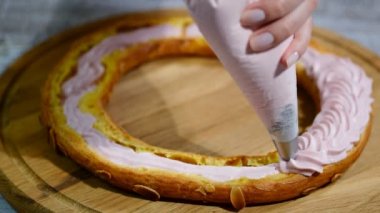 Bir Paris Brest pasta yarısı. Arka plan: bir pasta torba ile krem şanti dolum.