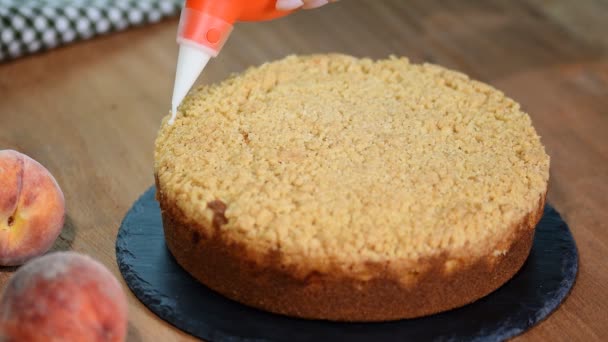 Szakács díszíti a tortát a porcukrot, a csővezeték táskát. Karamell cukor morzsa nyári őszibarack pite — Stock videók