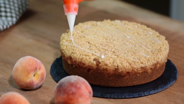 Cozinhe decorando um bolo com açúcar de confeiteiro com um saco de tubulação. Torta de pêssego de verão com migalha de açúcar de caramelo . — Vídeo de Stock