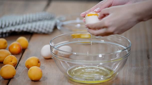 Femme mains cassant un oeuf pour séparer le blanc d'oeuf et jaunes et coquilles d'oeuf à l'arrière-plan . — Video