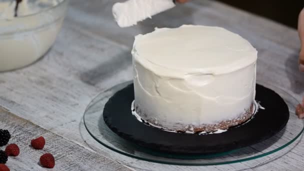 用白铲把黄油奶油涂在巧克力蛋糕上的手合上. — 图库视频影像