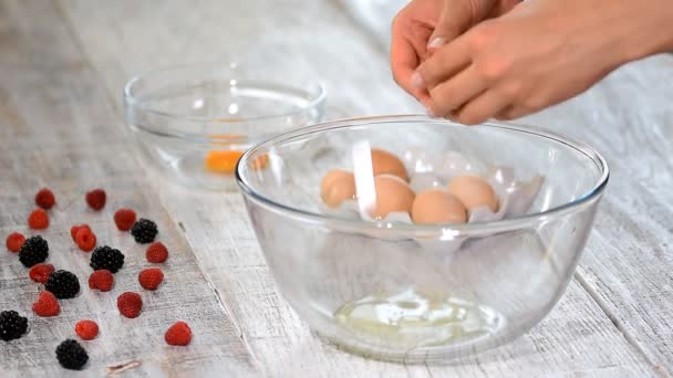 Kadın el ayırmak için bir yumurta kırma beyaz ve sarısı ve yumurta kabukları arka plan, yumurta. — Stok video