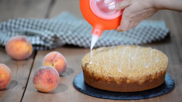 Cozinhe decorando um bolo com açúcar de confeiteiro com um saco de tubulação. Torta de pêssego de verão com migalha de açúcar de caramelo . — Vídeo de Stock