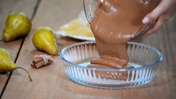 Žena kuchař ruce lití těsta do zapékací misky. Takže čokoládový koláč s hruškami. — Stock video