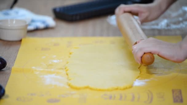 Les mains des femmes roulent la pâte sur la table de cuisine . — Video