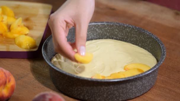 Процесс приготовления персикового пирога. Женщина положила свежий персик на тесто . — стоковое видео