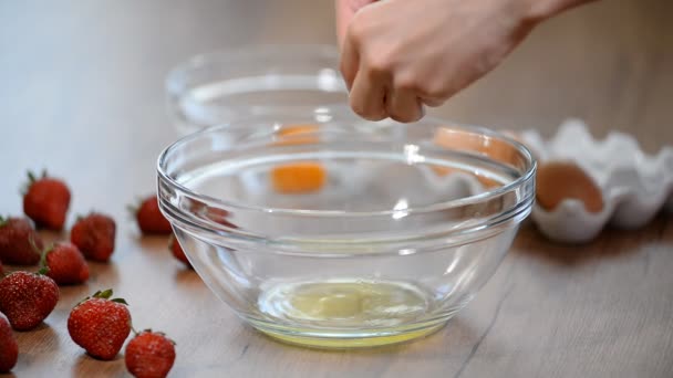 Femme mains cassant un oeuf pour séparer le blanc d'oeuf et jaunes et coquilles d'oeuf à l'arrière-plan . — Video