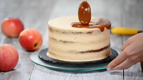 Mujer joven aplicando salsa de caramelo en la deliciosa torta casera en la mesa. Delicioso pastel con relleno de manzana y crema batida . — Vídeos de Stock