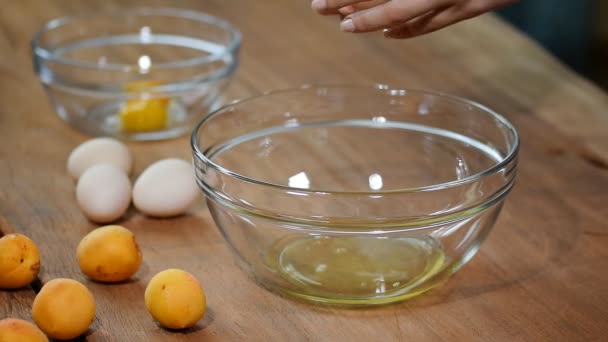 Mujer manos rompiendo un huevo para separar clara de huevo y yemas y cáscaras de huevo en el fondo . — Vídeos de Stock