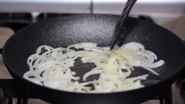 女性は、台所で鍋にタマネギをフライパン. — ストック動画