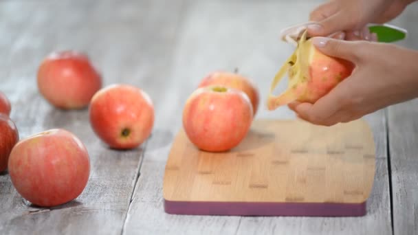 Handen een koken appel peeling op een houten bord — Stockvideo
