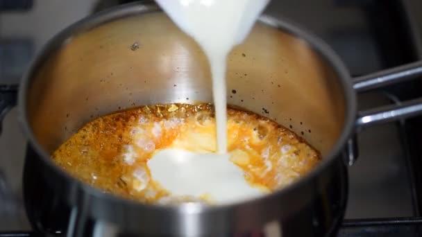 Cozinhar molho de caramelo. Despejando chantilly no caramelo . — Vídeo de Stock