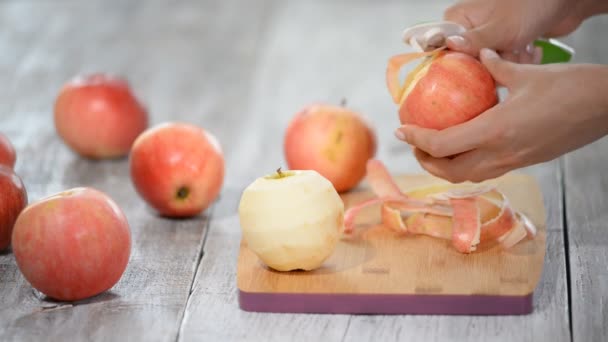 Yemek elma bir ahşap tahta üzerinde peeling eller. — Stok video