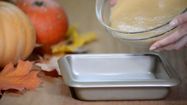 Femme verser de la pâte dans un moule pour faire un gâteau à la citrouille à la maison . — Video