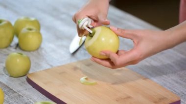 Yemek elma bir ahşap tahta üzerinde peeling eller.