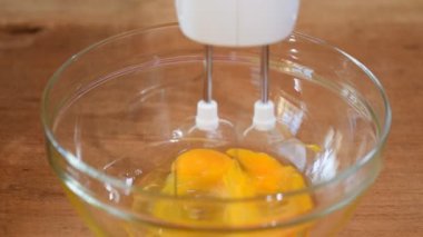 Dövülmüş yumurta bir kapta Mikser çırpma aletleri ile. Kahverengi kase içine dökme şeker.