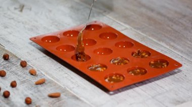 Bir kadın bir karamel ve doldurma fındık silikon kalıp içine koyar.