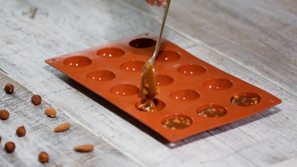 A woman puts in the silicone mold a caramel and nuts filling. — Stock Video