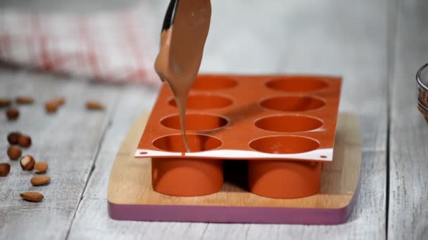 Frauenhände füllen eine Silikonform mit einer Schokoladenmousse. Herstellung von französischem Dessert. — Stockvideo