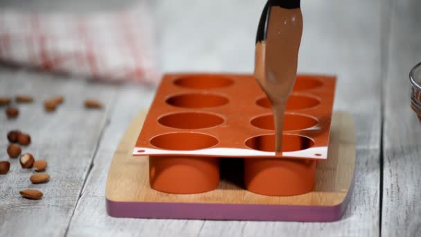 Manos femeninas llenando un molde de silicona con una mousse de chocolate. Hacer postre francés . — Vídeos de Stock