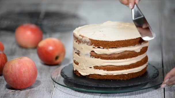 Pâtisserie féminine méconnaissable cuisinier serrant crème sur gâteau appétissant couche dans la cuisine . — Video