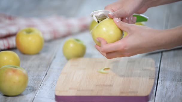 Mani che sbucciano una mela da cucina su una tavola di legno . — Video Stock