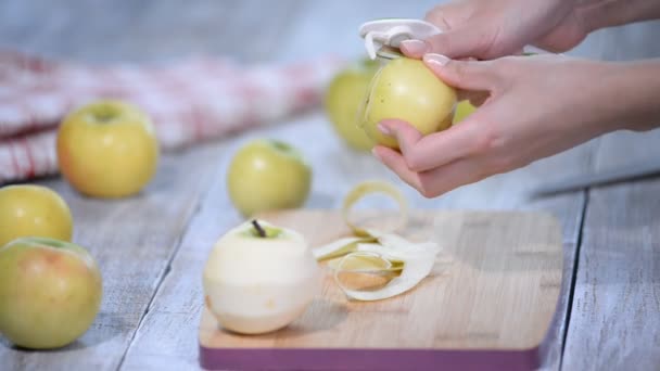 Handen een koken appel peeling op een houten bord. — Stockvideo